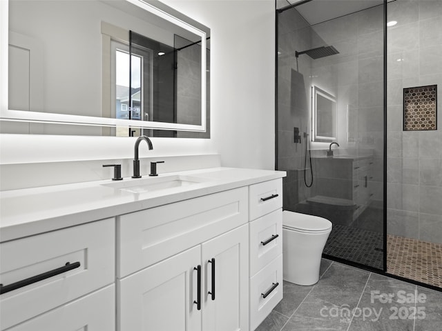 bathroom featuring toilet, tile patterned floors, a tile shower, and vanity