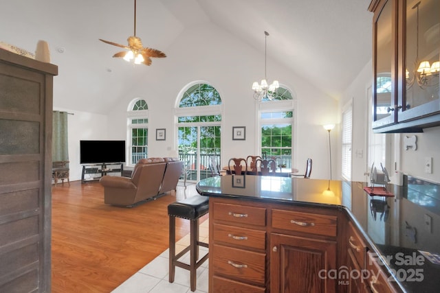 kitchen with a peninsula, dark countertops, high vaulted ceiling, and light wood-style floors