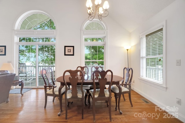 dining area featuring light wood finished floors, lofted ceiling, visible vents, an inviting chandelier, and baseboards