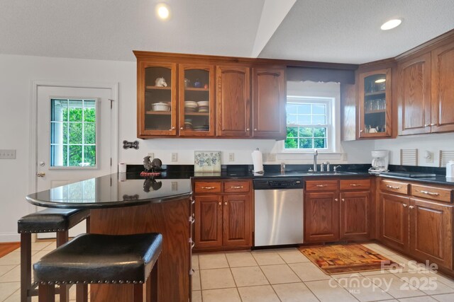 kitchen with dishwasher, a breakfast bar area, dark countertops, and a sink