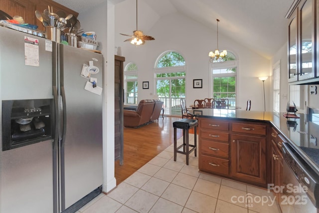 kitchen with light tile patterned floors, open floor plan, a peninsula, stainless steel appliances, and high vaulted ceiling