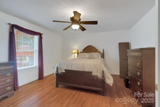 bedroom with light wood-style floors, baseboards, and a textured ceiling