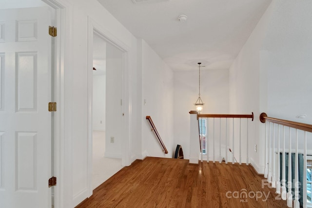 corridor with wood finished floors and an upstairs landing