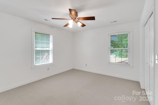 unfurnished room with baseboards, visible vents, and light colored carpet