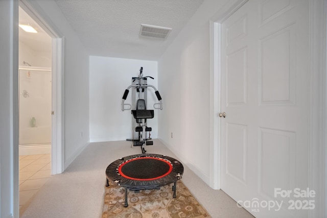 workout area with a textured ceiling, visible vents, and baseboards