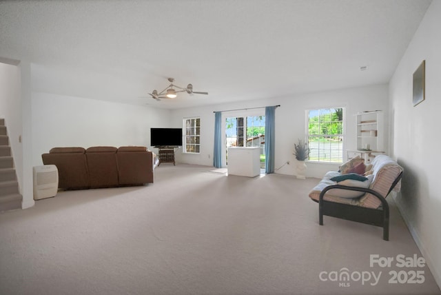 living room featuring carpet floors, stairs, and a ceiling fan