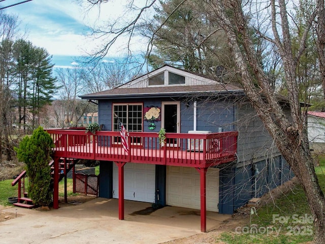 exterior space featuring a deck, roof with shingles, concrete driveway, a garage, and stairs