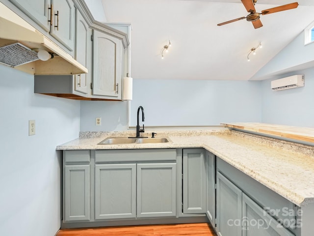 kitchen featuring a sink, lofted ceiling, gray cabinetry, and a wall mounted air conditioner