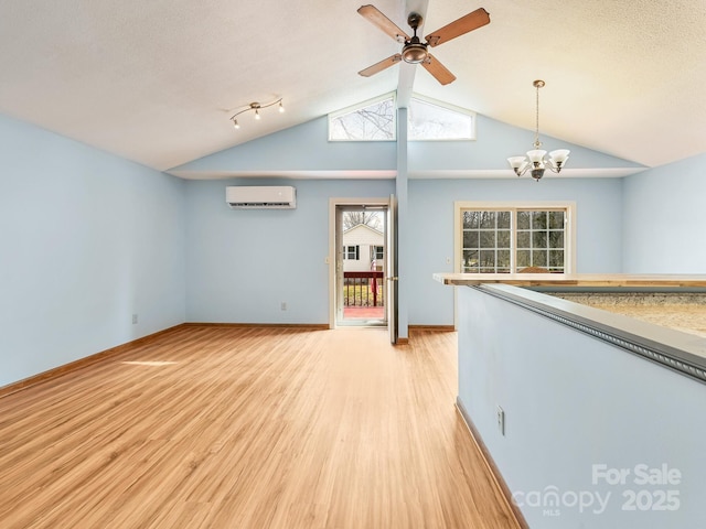 unfurnished living room with baseboards, light wood-style floors, vaulted ceiling, and a wall mounted AC