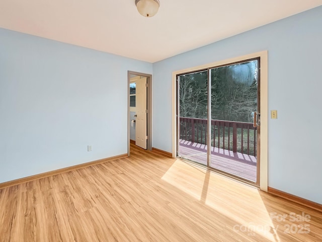 spare room with baseboards and light wood-style flooring