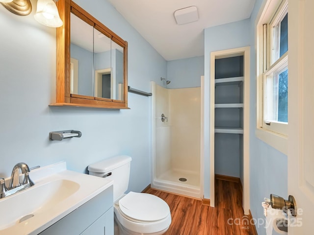 full bath with a shower, toilet, wood finished floors, and vanity