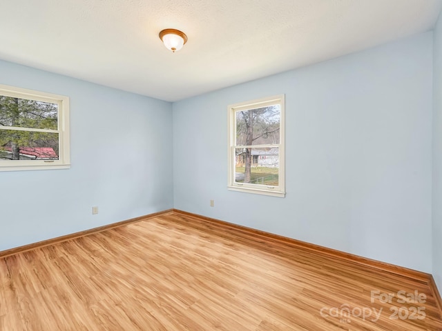 spare room featuring baseboards and wood finished floors