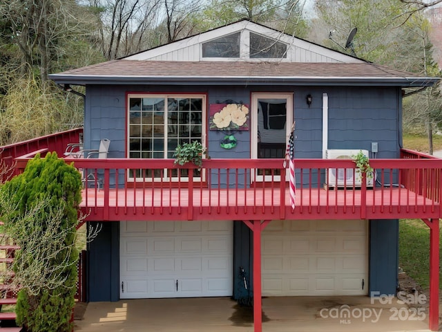 view of front of house featuring an attached garage, driveway, and a shingled roof