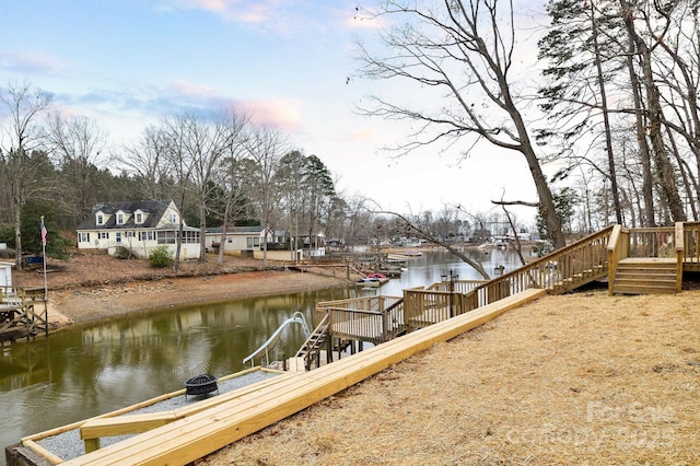 view of dock with an outdoor fire pit and a deck with water view