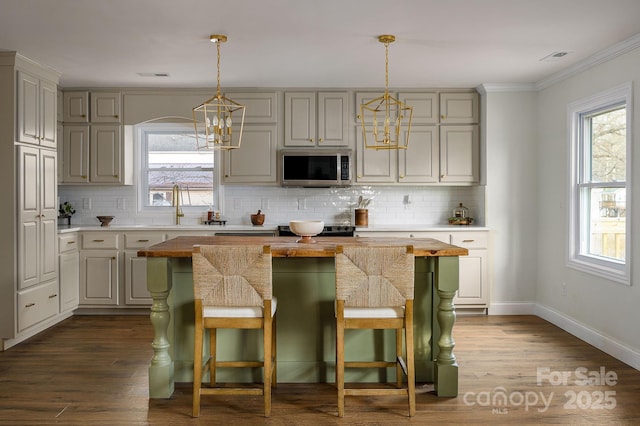 kitchen featuring tasteful backsplash, dark wood finished floors, stainless steel microwave, and a sink