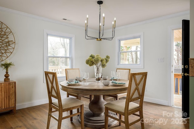 dining room with crown molding, light wood finished floors, and a healthy amount of sunlight