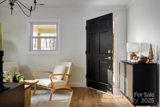 entryway featuring baseboards, visible vents, wood finished floors, an inviting chandelier, and crown molding