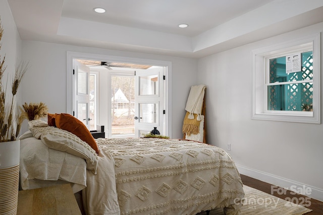 bedroom with recessed lighting, a raised ceiling, baseboards, and wood finished floors