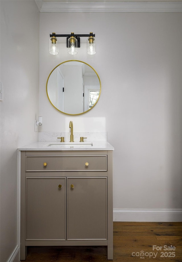 bathroom with crown molding, wood finished floors, vanity, and baseboards