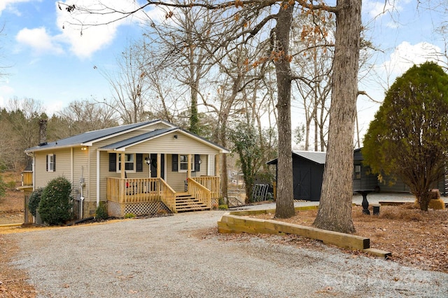 view of front facade with covered porch, a storage unit, and an outbuilding