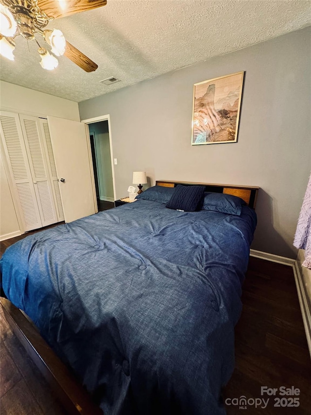 bedroom featuring baseboards, visible vents, ceiling fan, wood finished floors, and a textured ceiling