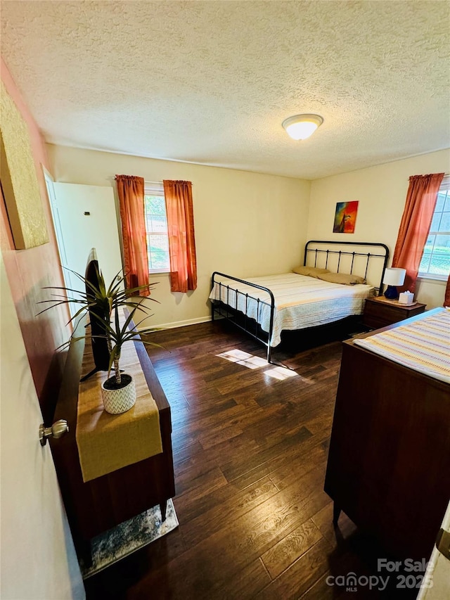 bedroom with a textured ceiling, baseboards, and hardwood / wood-style floors