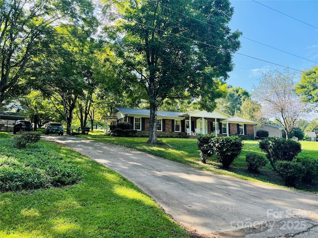 single story home with a front yard, covered porch, brick siding, and driveway