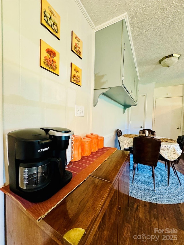 interior space with a textured ceiling, dark wood-type flooring, and crown molding