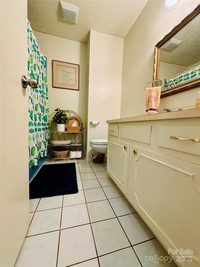 full bath featuring vanity, a textured ceiling, toilet, and tile patterned floors