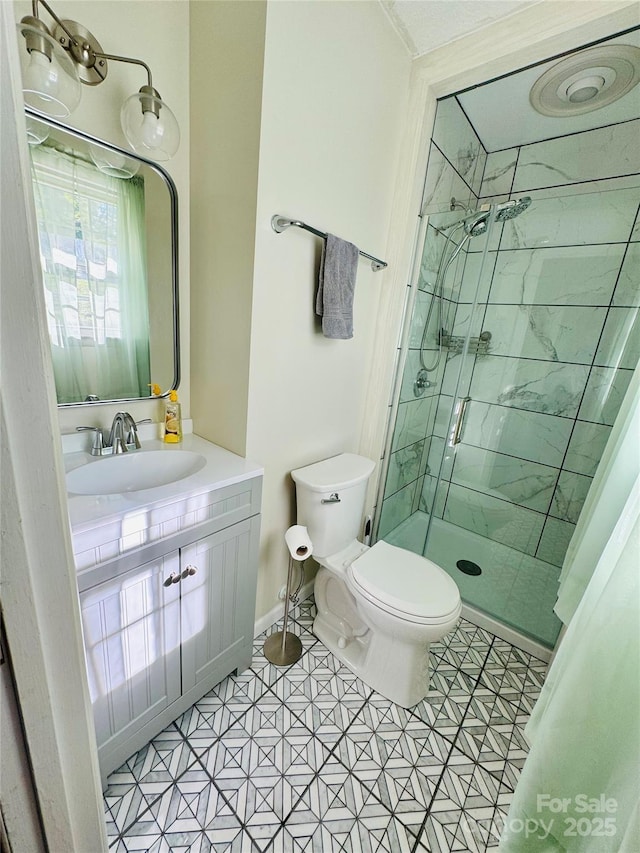 full bathroom featuring a stall shower, vanity, and toilet