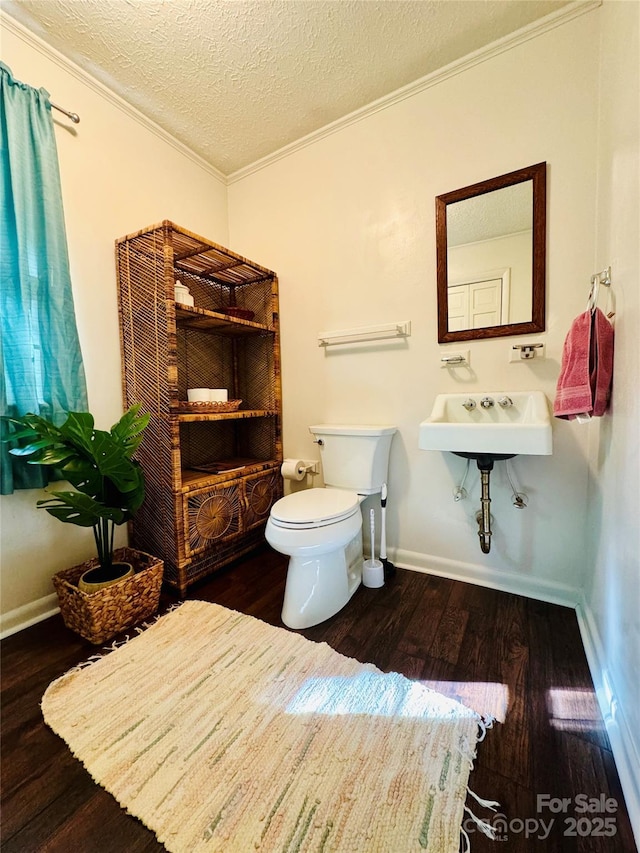 bathroom with toilet, ornamental molding, wood finished floors, a textured ceiling, and a sink