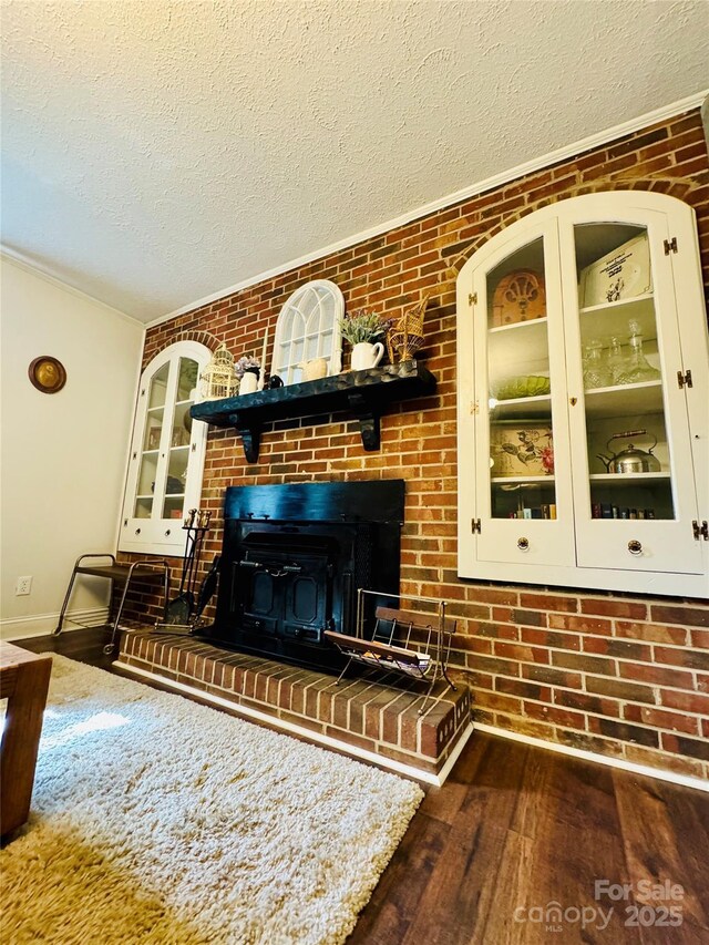 living room featuring brick wall, a fireplace, a textured ceiling, and hardwood / wood-style floors