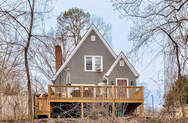 rear view of house featuring a chimney, a deck, cooling unit, and stucco siding