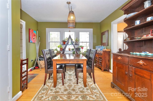 dining area with light wood-type flooring and baseboards