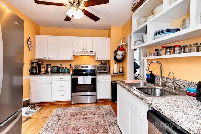 kitchen featuring light wood finished floors, appliances with stainless steel finishes, under cabinet range hood, open shelves, and a sink