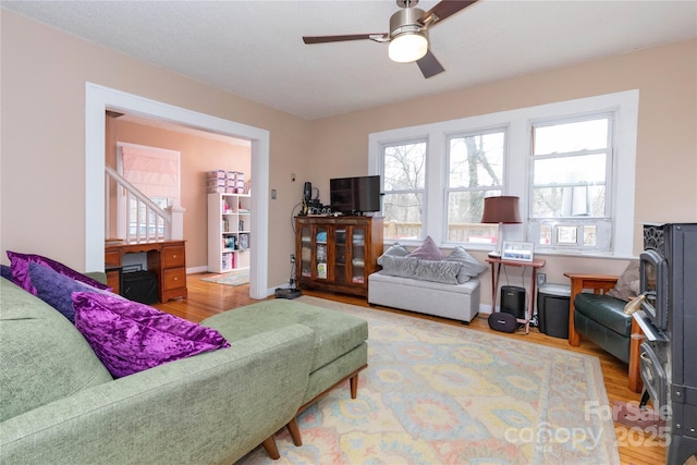 living room with light wood finished floors, ceiling fan, and baseboards