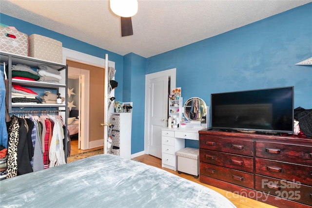 bedroom featuring ceiling fan, a textured ceiling, and wood finished floors