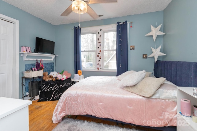 bedroom with a ceiling fan, a textured ceiling, visible vents, and wood finished floors