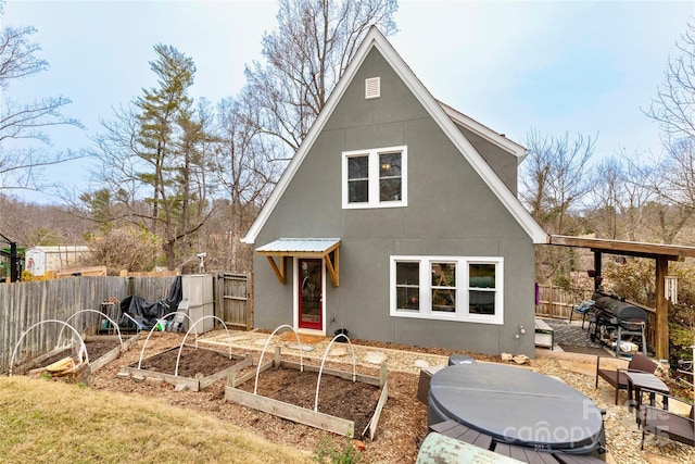 back of house featuring a garden, a patio, a fenced backyard, and stucco siding