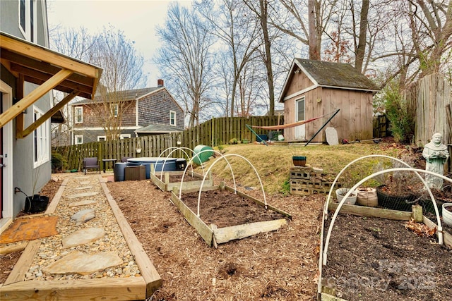 view of yard with a fenced backyard, a vegetable garden, an outdoor structure, and a shed