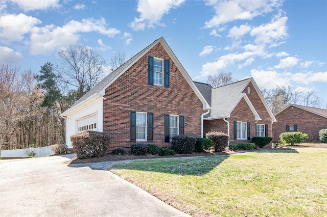 traditional home with fence, concrete driveway, a front yard, a garage, and brick siding