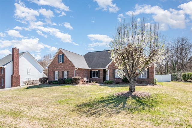 traditional-style home with a front lawn, fence, brick siding, and roof with shingles