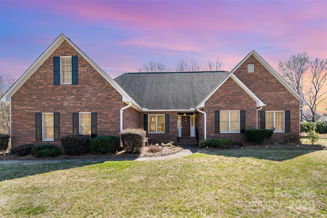 traditional home with a front lawn, brick siding, and roof with shingles