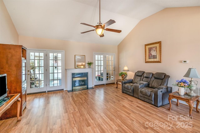 living room featuring a fireplace, plenty of natural light, french doors, and light wood finished floors