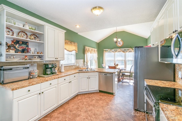 kitchen with a peninsula, open shelves, a sink, white cabinets, and appliances with stainless steel finishes