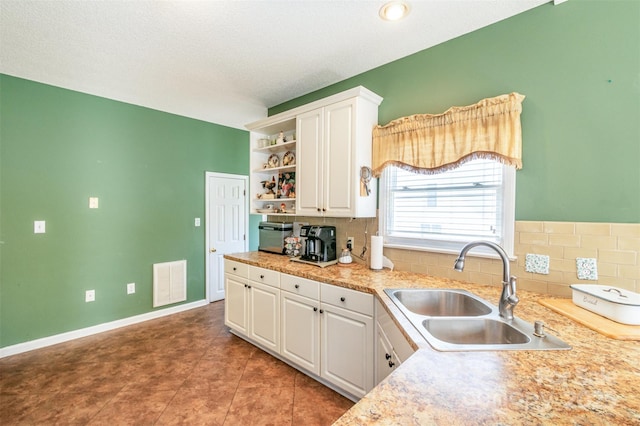 kitchen featuring visible vents, a sink, open shelves, white cabinets, and decorative backsplash