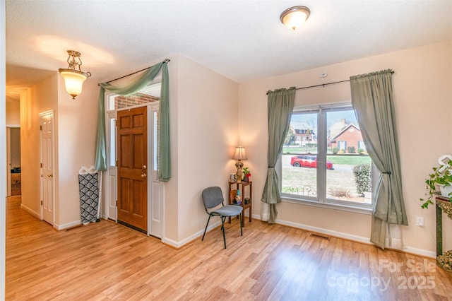 interior space featuring baseboards, visible vents, and light wood finished floors