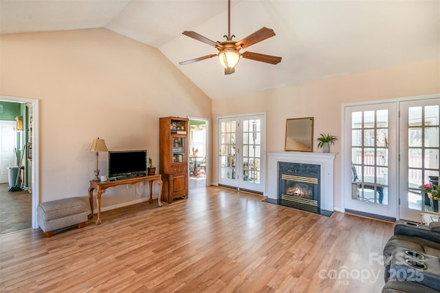 living area with a ceiling fan, light wood-type flooring, a high end fireplace, and a healthy amount of sunlight