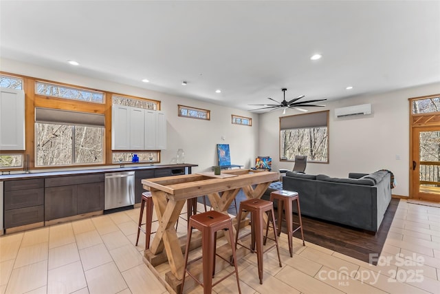 kitchen with recessed lighting, white cabinetry, stainless steel dishwasher, and a wall mounted AC