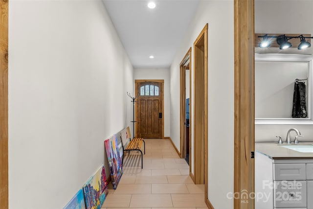 corridor with tile patterned flooring, recessed lighting, and a sink